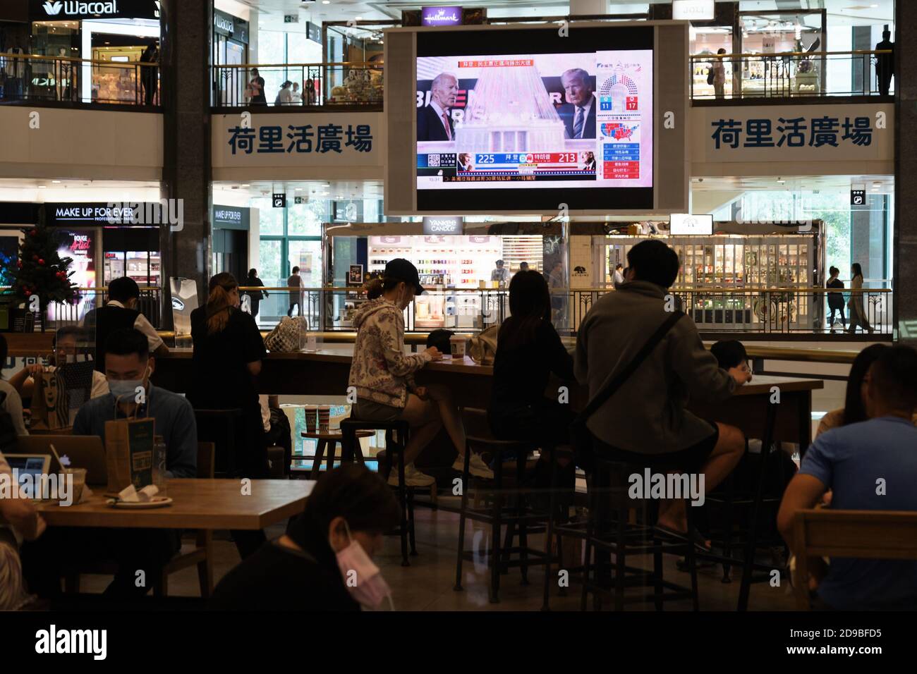 A screen broadcasts the live news report of the US Presidential elections at a shopping mall. Stock Photo