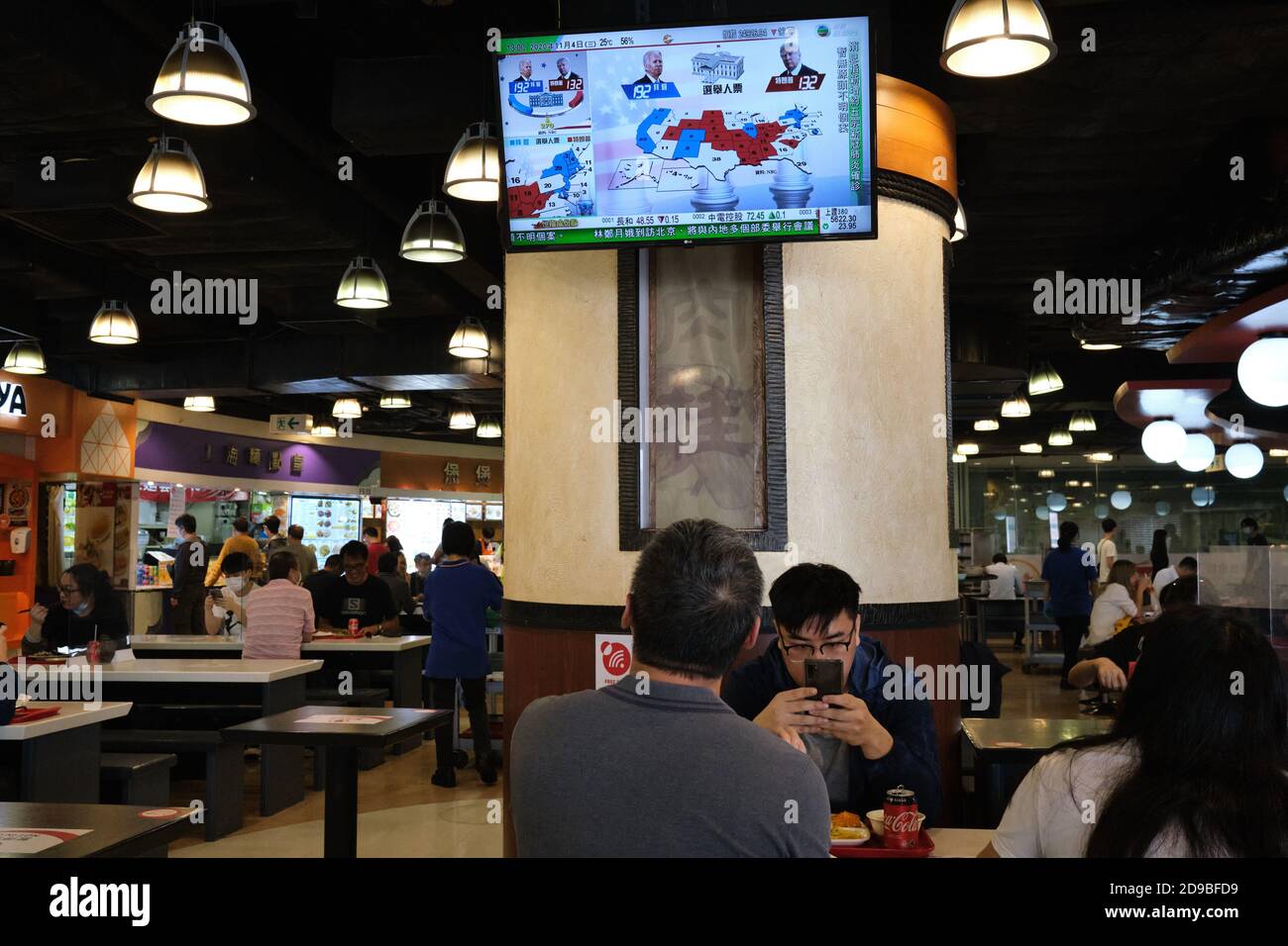 A man watches live news report of the US Presidential elections at a food court  in Hong Kong as U.S.'s future policies on Hong Kong may be affected. Stock Photo