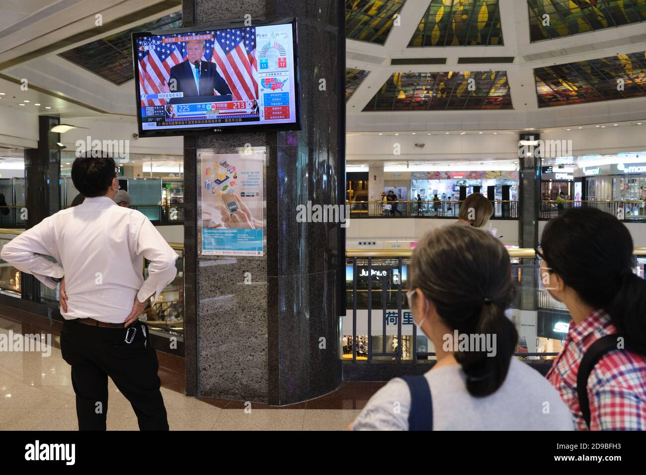 People watch live news report of the US Presidential elections at a shopping mall in Hong Kong as U.S.'s future policies on Hong Kong may be affected. Stock Photo