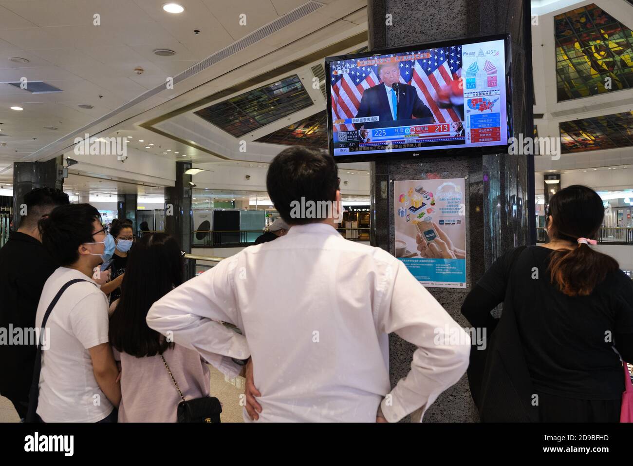People watch live news report of the US Presidential elections at a shopping mall in Hong Kong as U.S.'s future policies on Hong Kong may be affected. Stock Photo