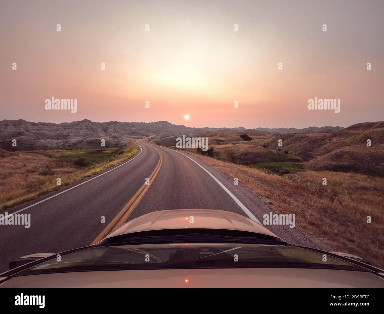 Car driving along road at sunset during wildfires, Badlands National Park, South Dakota, USA Stock Photo