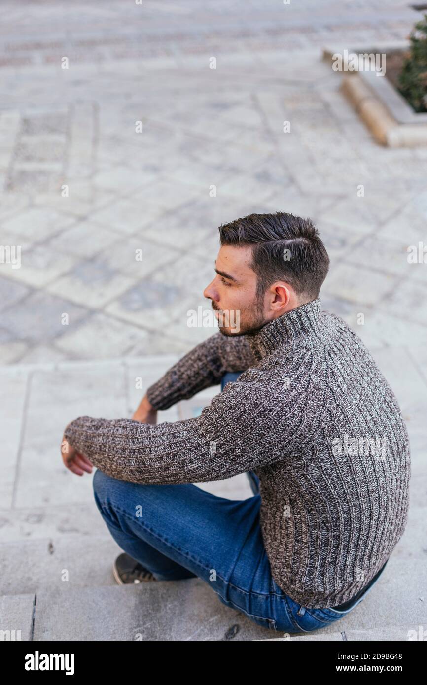 White man in autumn vest sitting on a single-place fountain Stock Photo ...