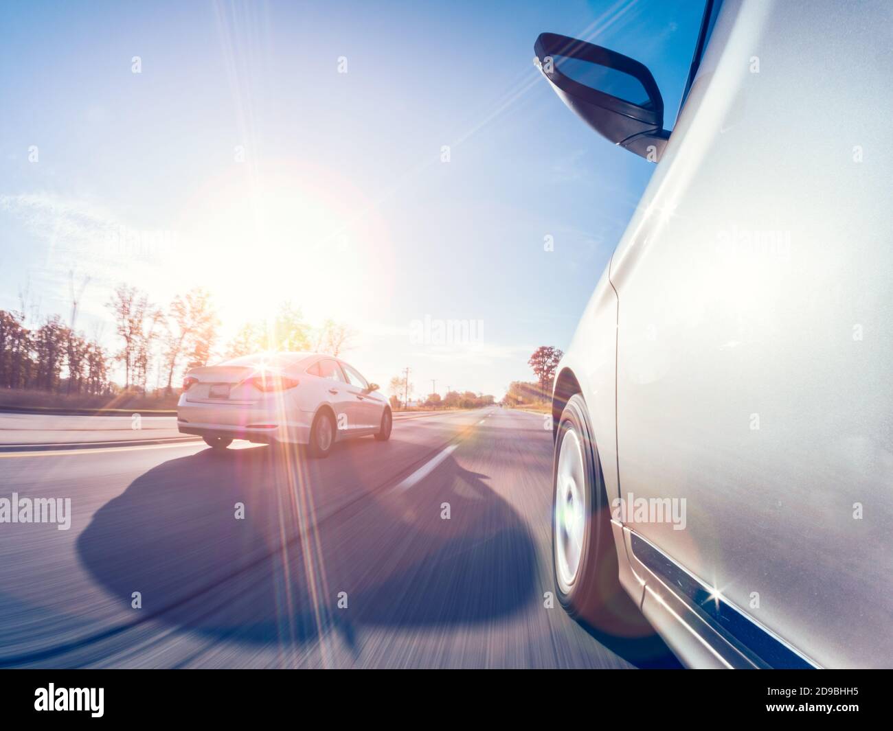 Two cars driving along an autumn road, USA Stock Photo