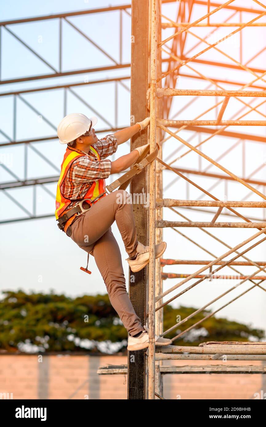 Construction worker climbing scaffolding, Thailand Stock Photo