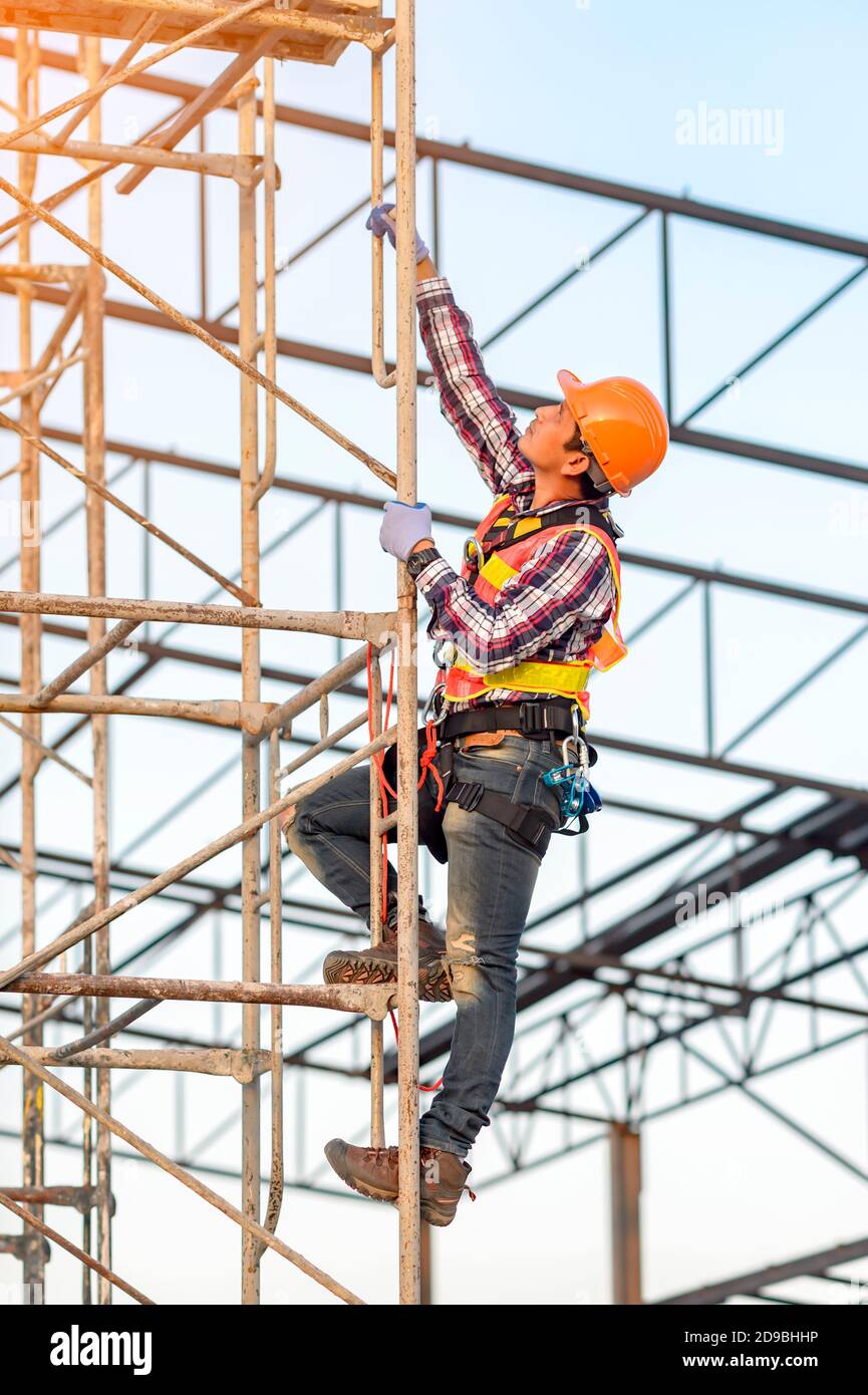 Construction worker climbing scaffolding, Thailand Stock Photo