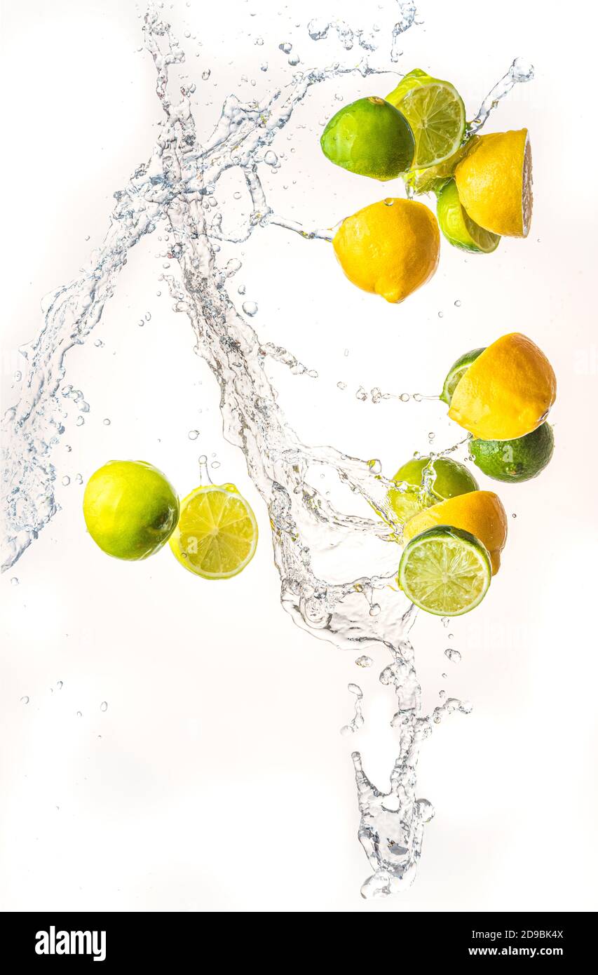 Fresh limes and lemons with water splash in midair, isolated on white background Stock Photo