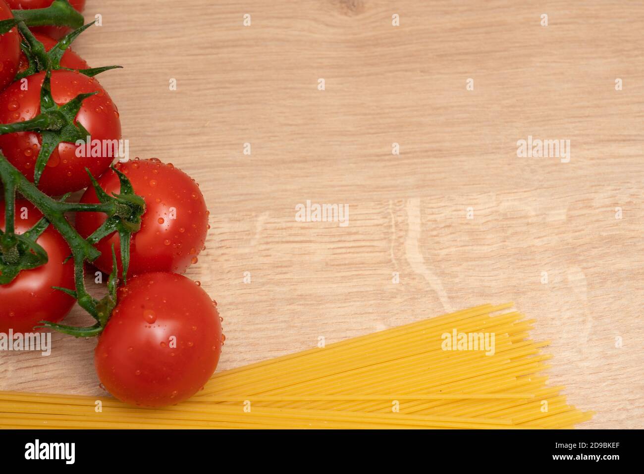Italian pasta spaghetti and juicy organic tomatoes close-up with blank copyspace for advertising text on cutting board as fresh cooking concept Stock Photo