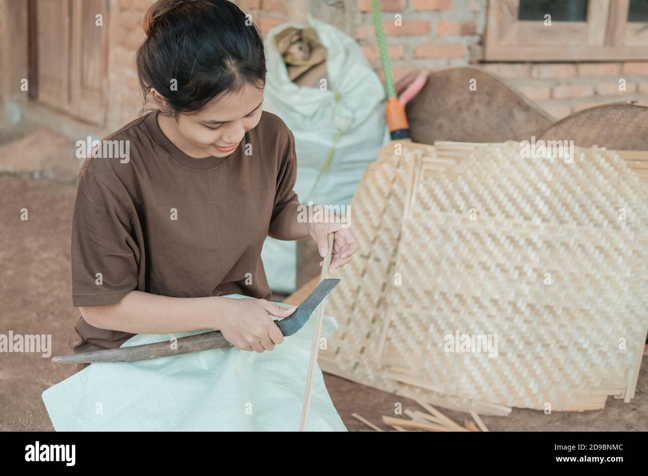 working women use knives to make bamboo mats at home Stock Photo