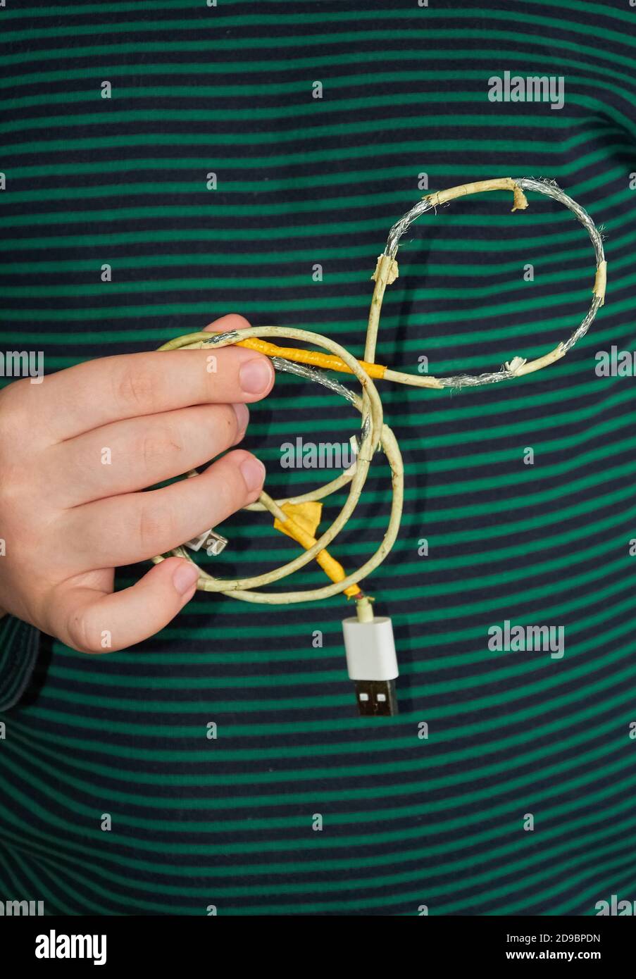 The child is holding an old torn USB cord in his hand. Close up Stock Photo