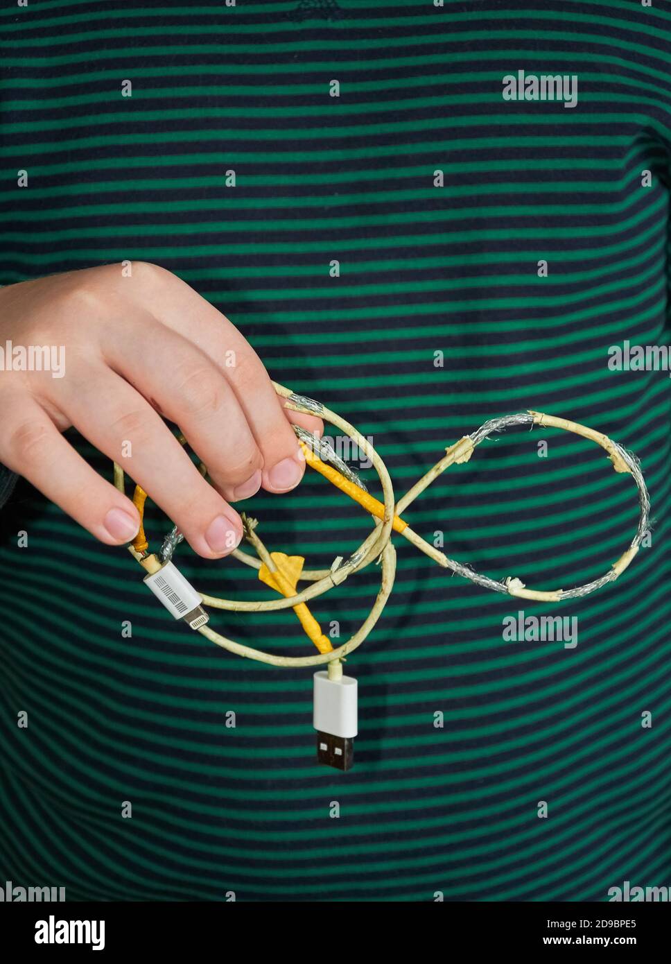 The child is holding an old torn USB cord in his hand. Close up Stock Photo