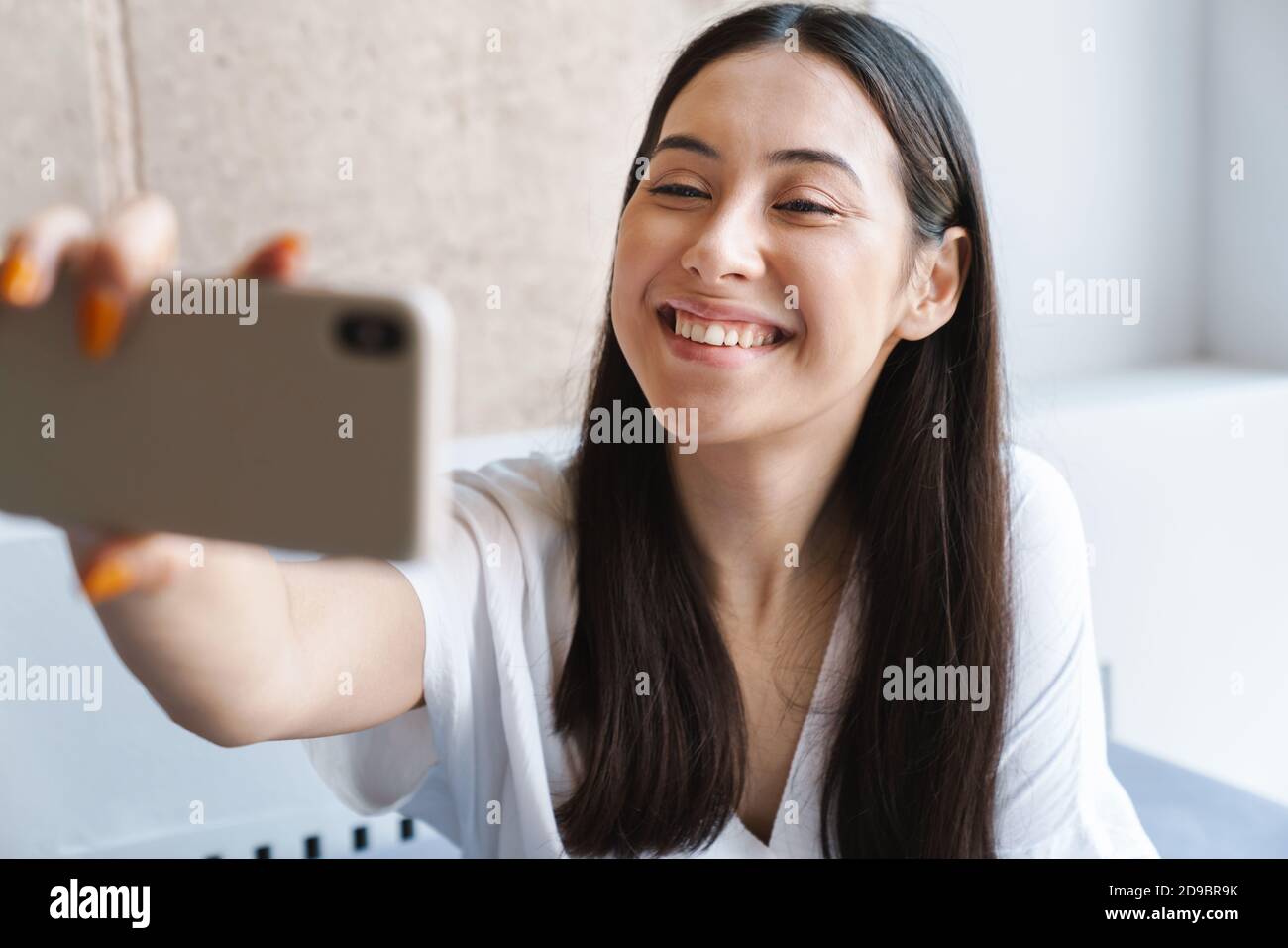 Happy youg woman taking a selfie while sitting on a couch at home Stock ...
