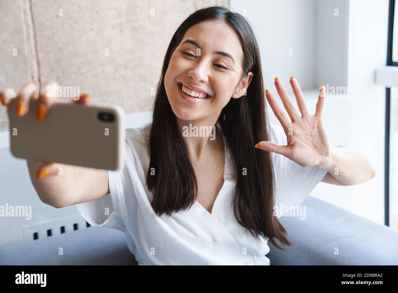 Happy youg woman taking a selfie while sitting on a couch at home Stock ...