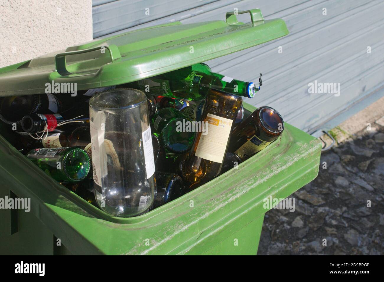 green glass garbage bin full of bottles Stock Photo