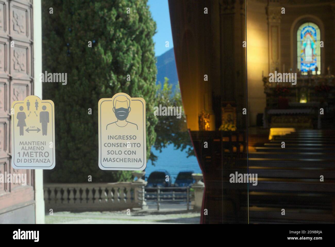 mask compulsory and keep distance signs on the door of a church in Italy Stock Photo