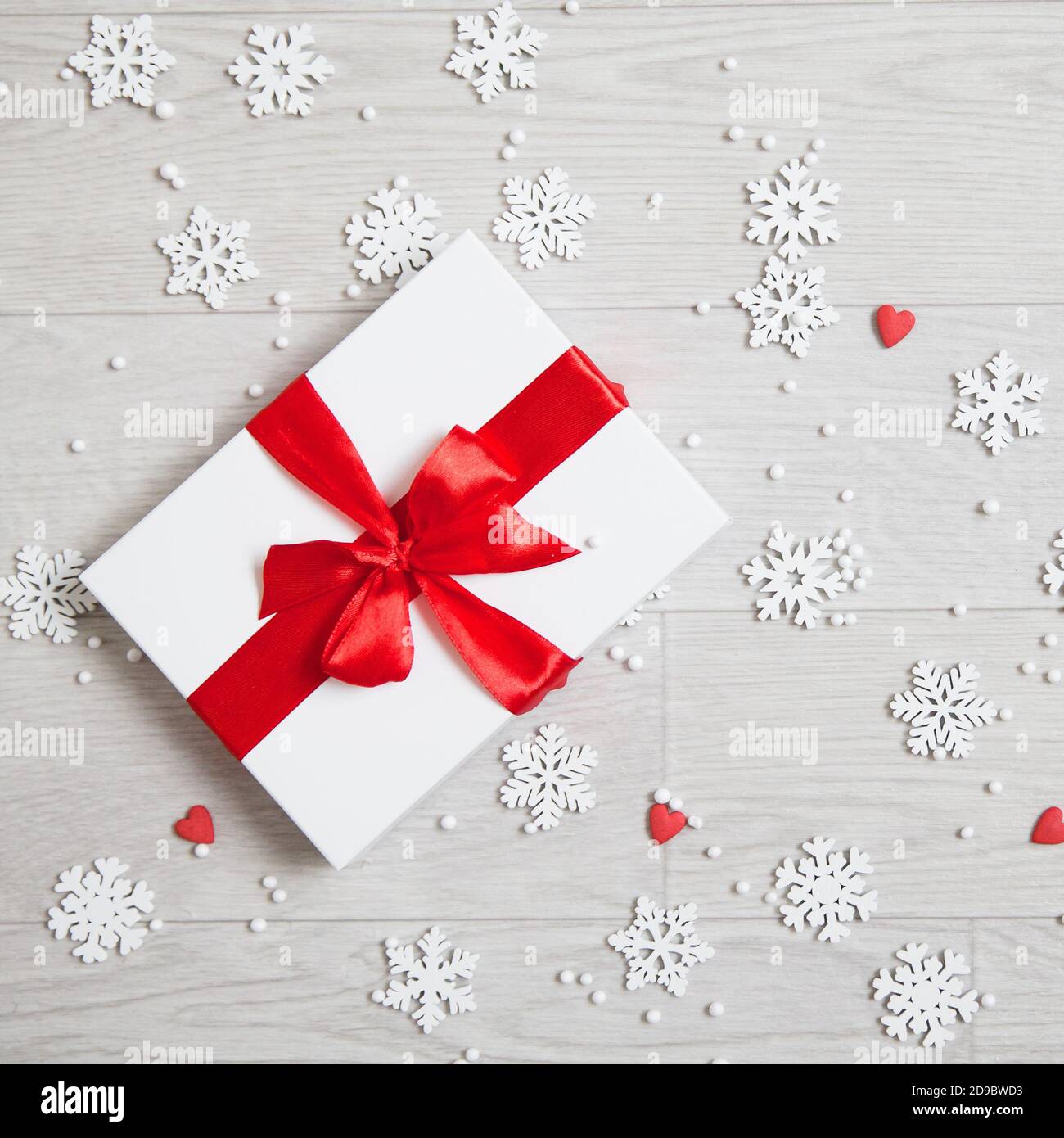 Gift with a red bow and snowflakes. New Year's gift. White box with red ribbon. Stock Photo