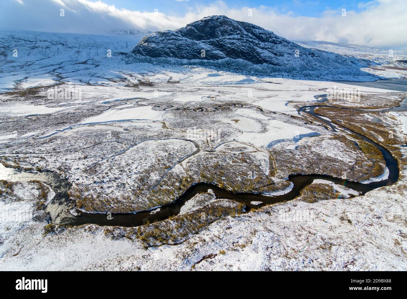 Aerial view of a river winding through an arctic landscape with snow during autumn with Rásek mountain in Stora Sjöfallet National Park, Sweden Stock Photo