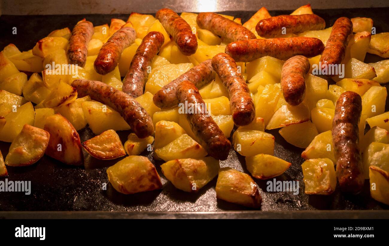 Traditional Nuremberg or Bavarian sausages baked in the oven with potatoes Stock Photo