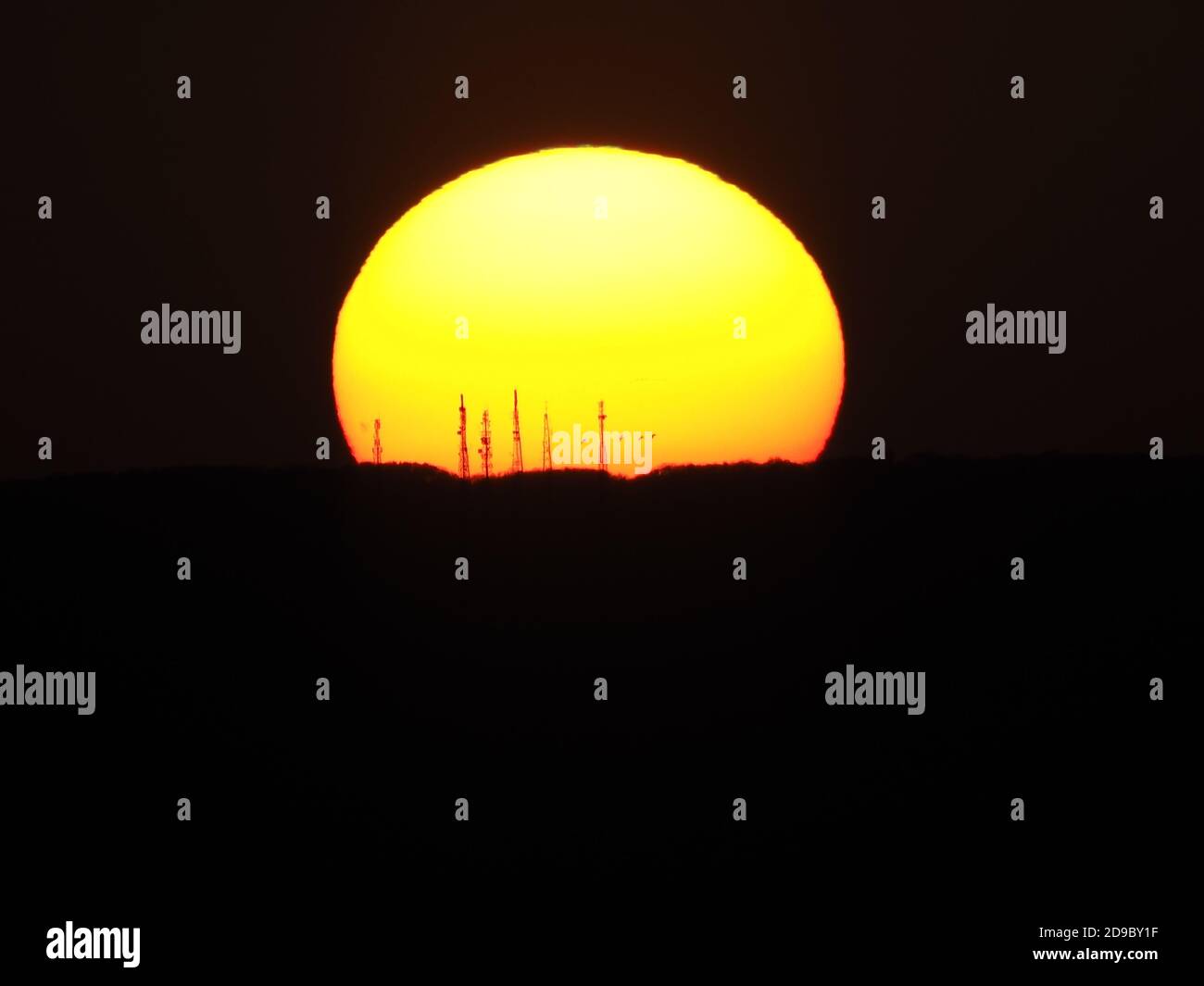 Minster on Sea, Kent, UK. 4th November, 2020. UK Weather: sunset behind the Sheppey Crossing as seen from Minster on Sea, Kent. The TV transmitter masts at Blue Bell Hill contained within the setting sun. Credit: James Bell/Alamy Live News Stock Photo