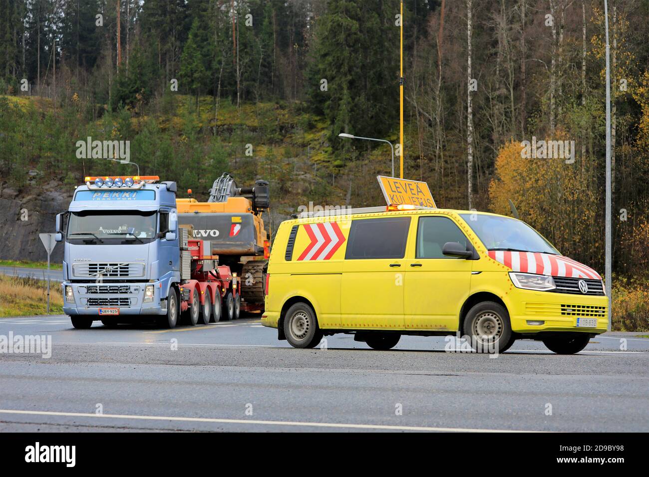 Pilot vehicle assisting Volvo FH semi trailer with oversize load transport of Volvo EC700CL crawler excavator. Forssa, Finland. Oct 30, 2020. Stock Photo