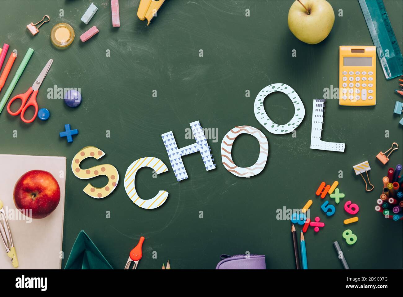 top view of frame with ripe apples and school supplies on green ...