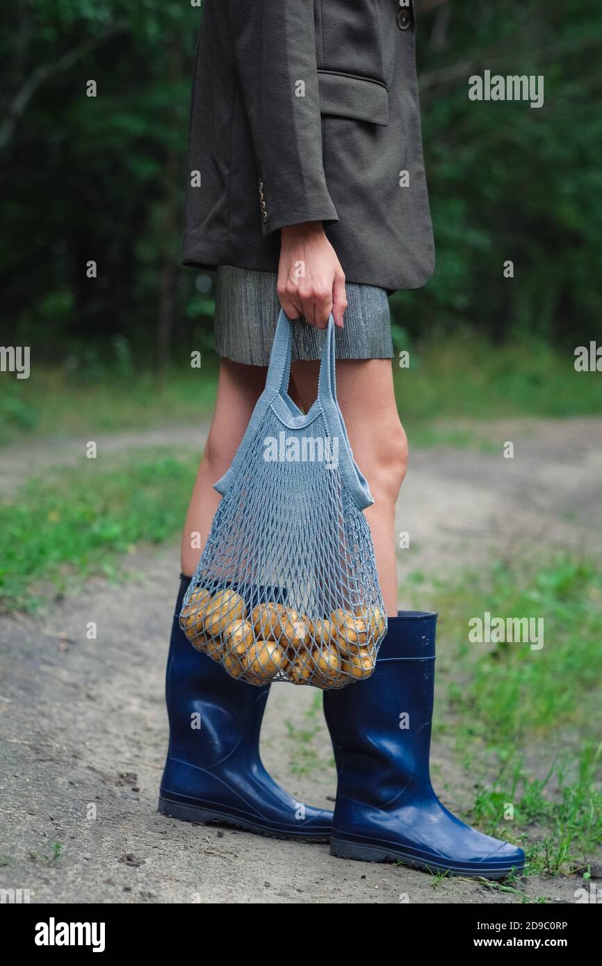 Woman holding string bag with potatoes. Stock Photo