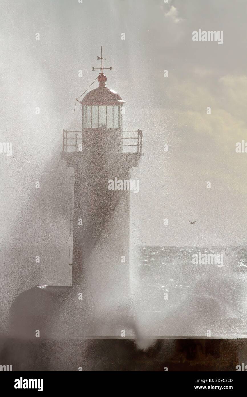 Old lighthouse at the mouth of the Douro River in semi backlight seeing the light filtered by the drops of salt water after a splash of wave Stock Photo