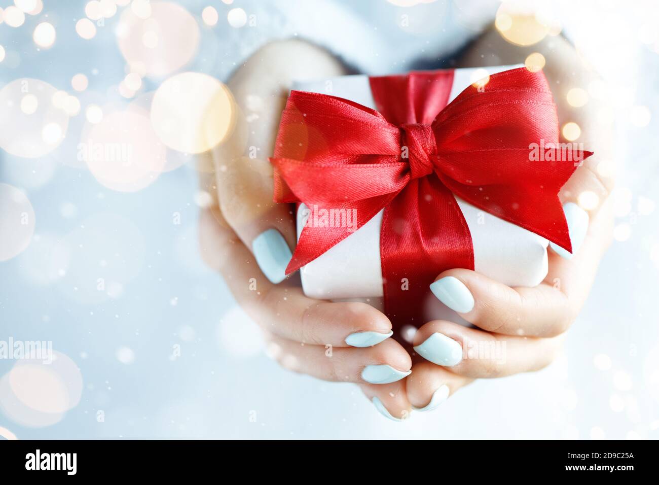 Gift box with red bow in womans hands Stock Photo