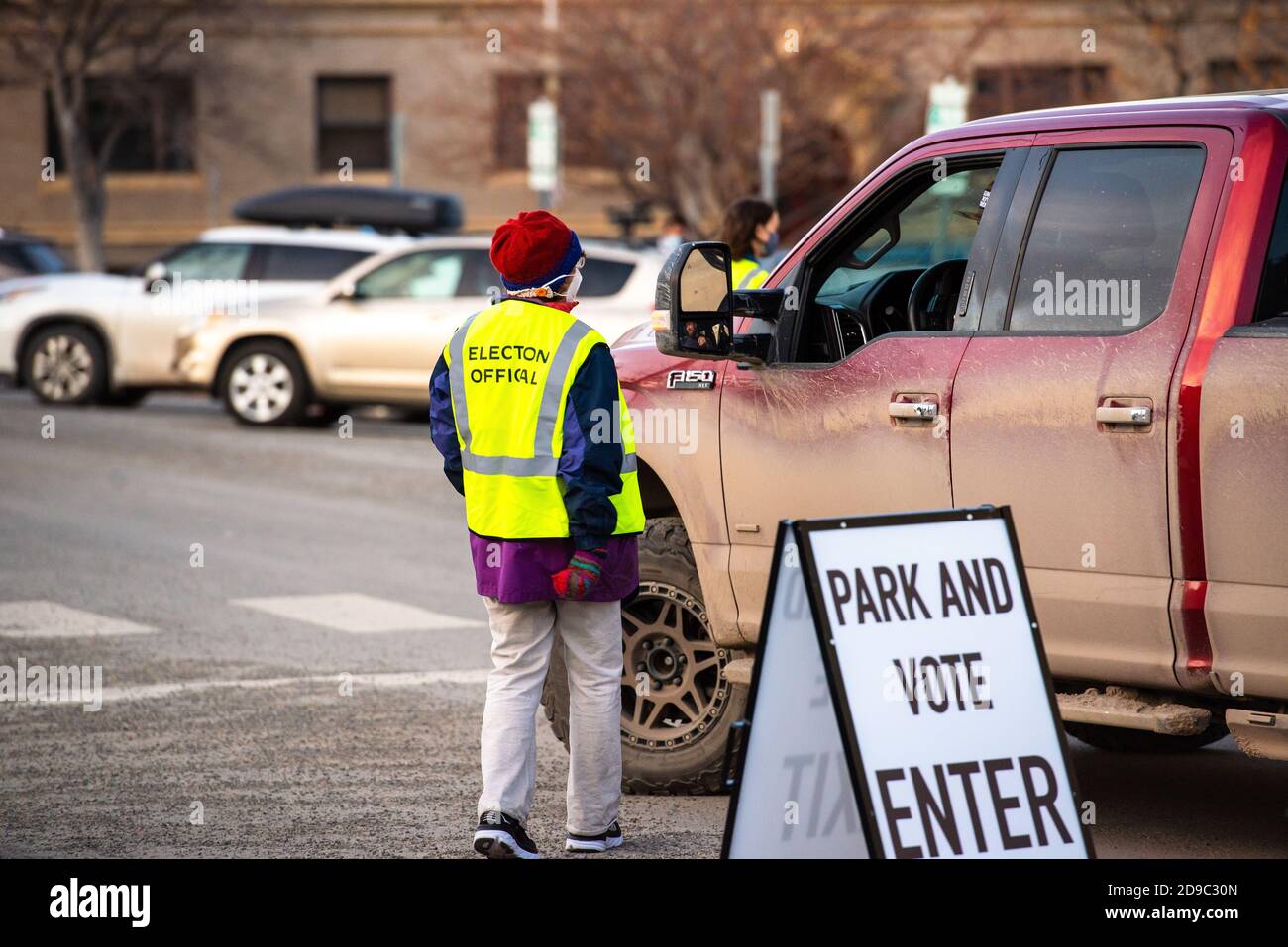 Helena, Montana / November 3, 2020: Woman poll worker helping voter at polling station, park vote in truck, presidential Election Day voting, people i Stock Photo