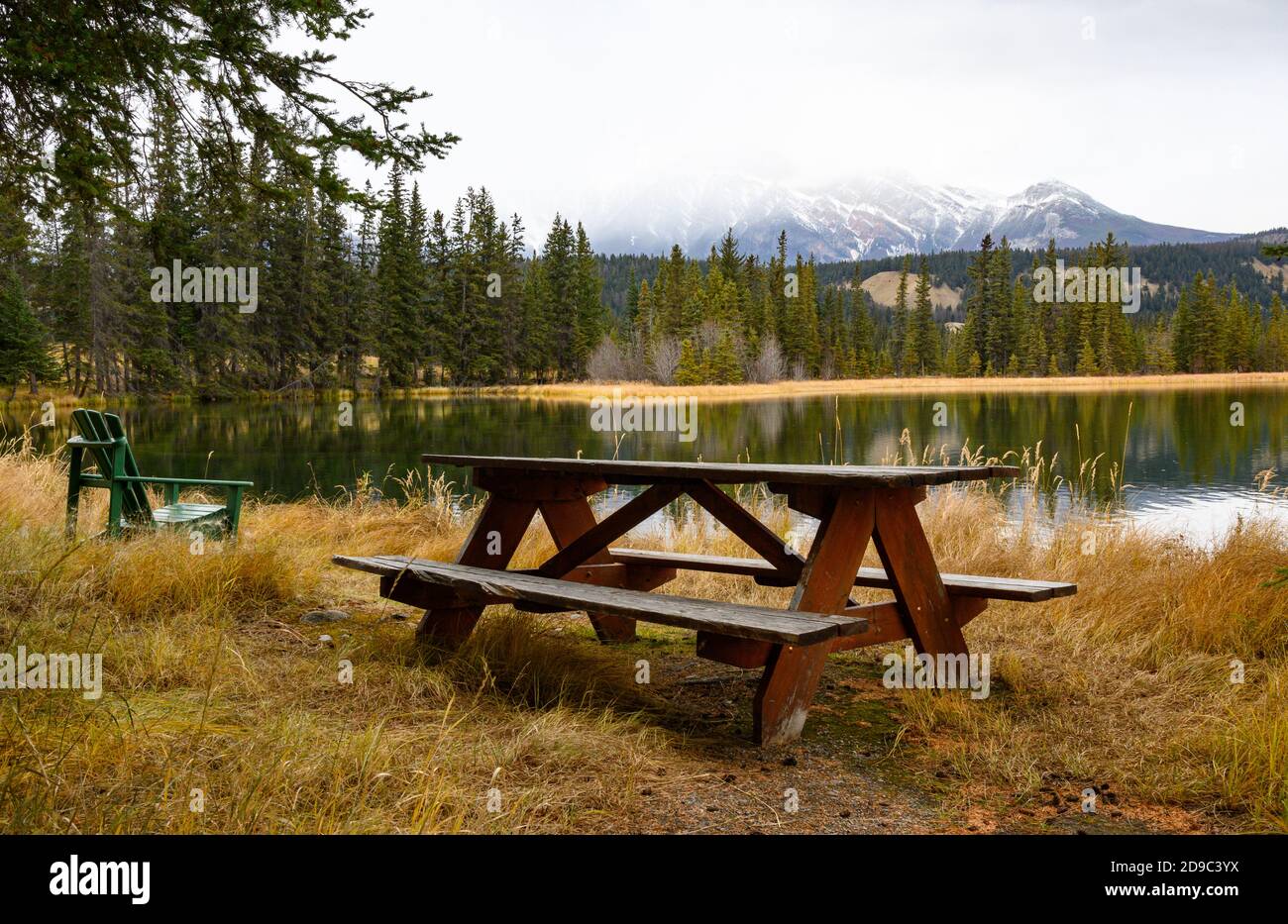 wooden picnic table and Adirondack chair near a lake in Jasper National Park Stock Photo