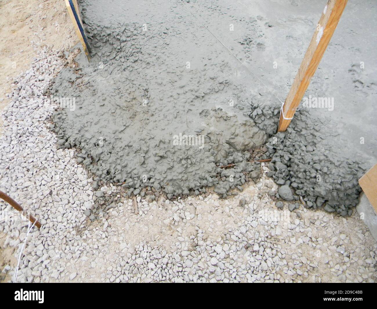 Pouring cement, concrete over gravel before laying paving slabs, installing patio pavers in the backyard of the house. Stock Photo