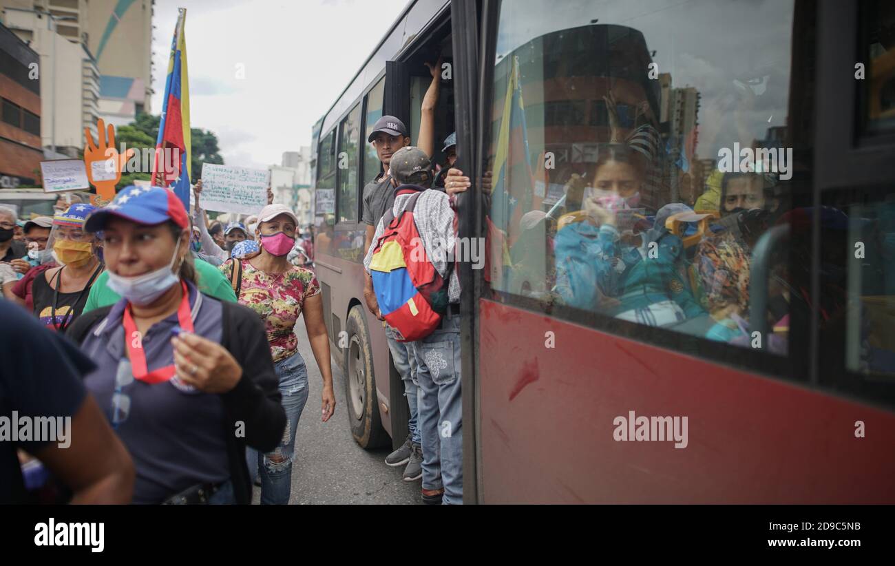 Caracas, Venezuela. 04th Nov, 2020. Bus drivers with masks watch demonstrators passing by with Venezuelan flags in the middle of the Corona pandemic. A union alliance had called for a protest by health and education workers for better salaries. Credit: Rafael Hernandez/dpa/Alamy Live News Stock Photo