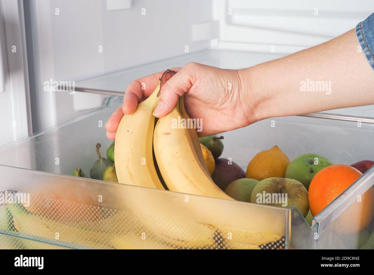 Woman getting fresh bananas from a fridge. Close up. Stock Photo