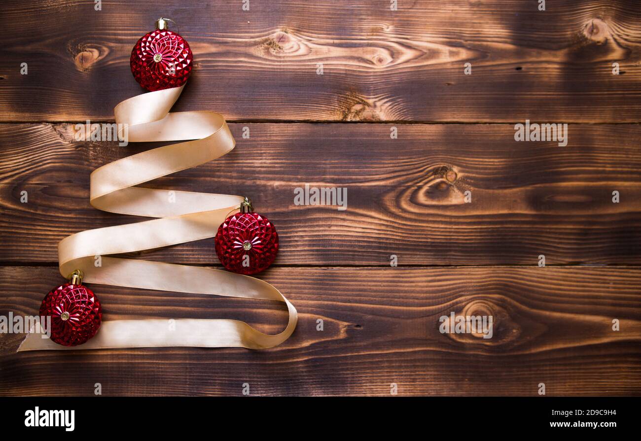 A Christmas tree made of gold ribbon decorated with red round toys on a ...