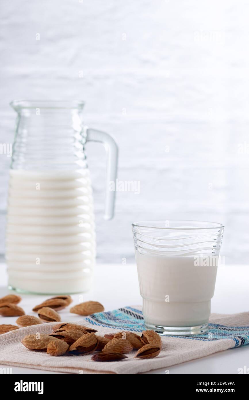 Almond milk in a glass with almonds on a white table Stock Photo