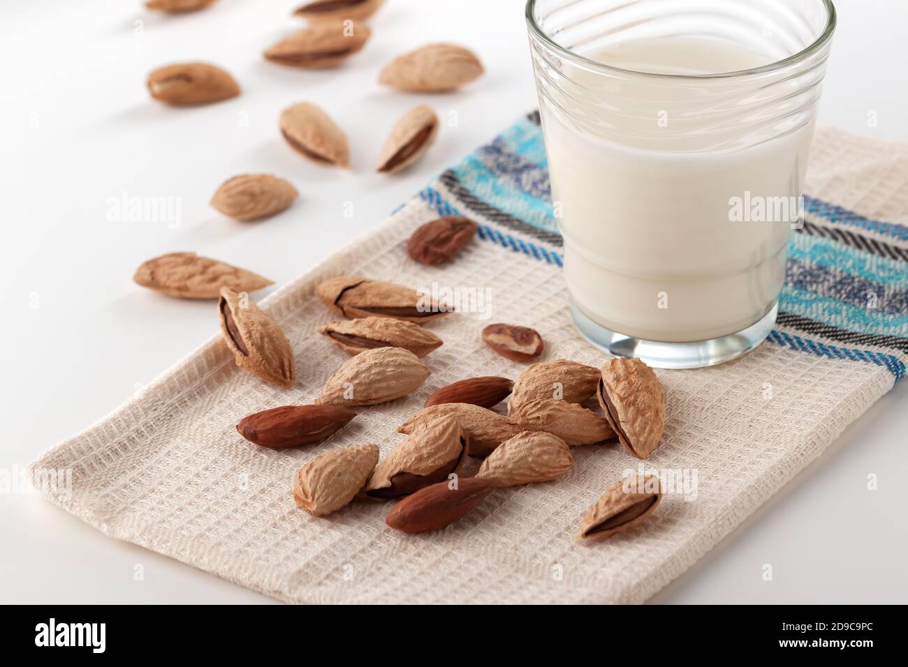 Almond milk in a glass with almonds on a white table Stock Photo