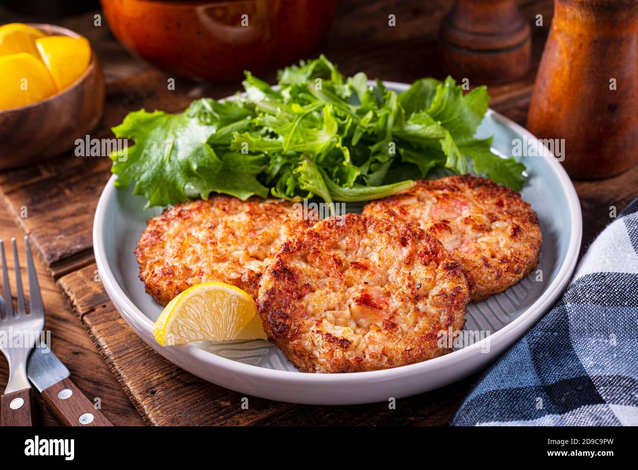 A plate of delicious crab cakes with spring mix salad and lemon garnish. Stock Photo