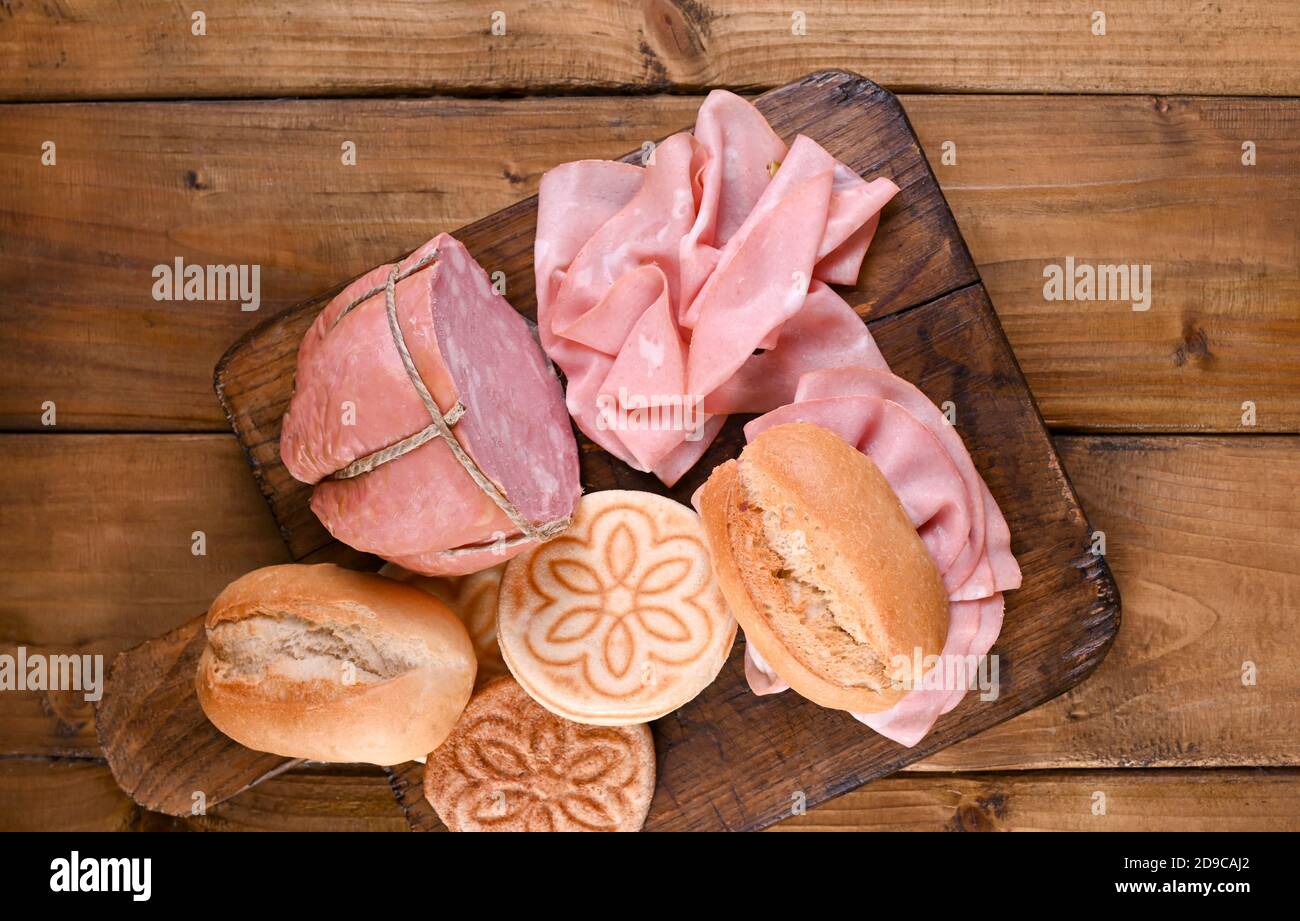 Mortadella and panino on a wooden table. Assorted breads of different types, Tigelle for traditional Italian sandwiches in the region of Emilia Romagna. Above. Copy space Stock Photo