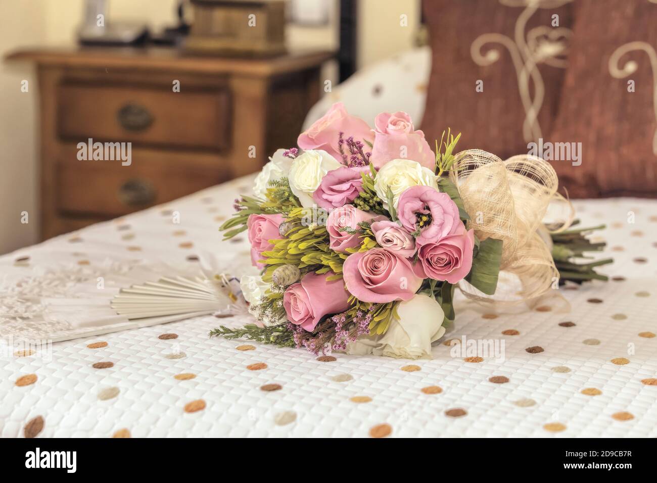 Bridal bouquet of roses on a bed of a blurred bedroom Stock Photo