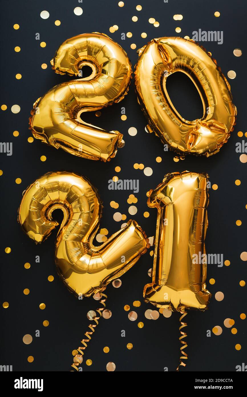 2021 balloon gold text on black background with golden confetti, festive decor. Happy New year eve invitation with Christmas gold foil balloons 2021 Stock Photo