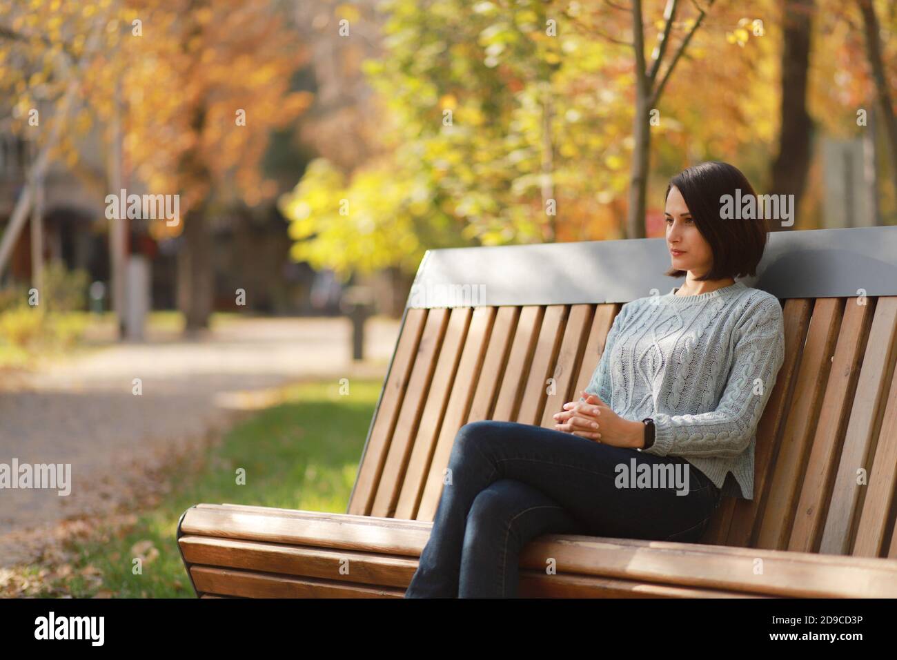 Young beautiful woman sitting on bench in autumn park Stock Photo - Alamy