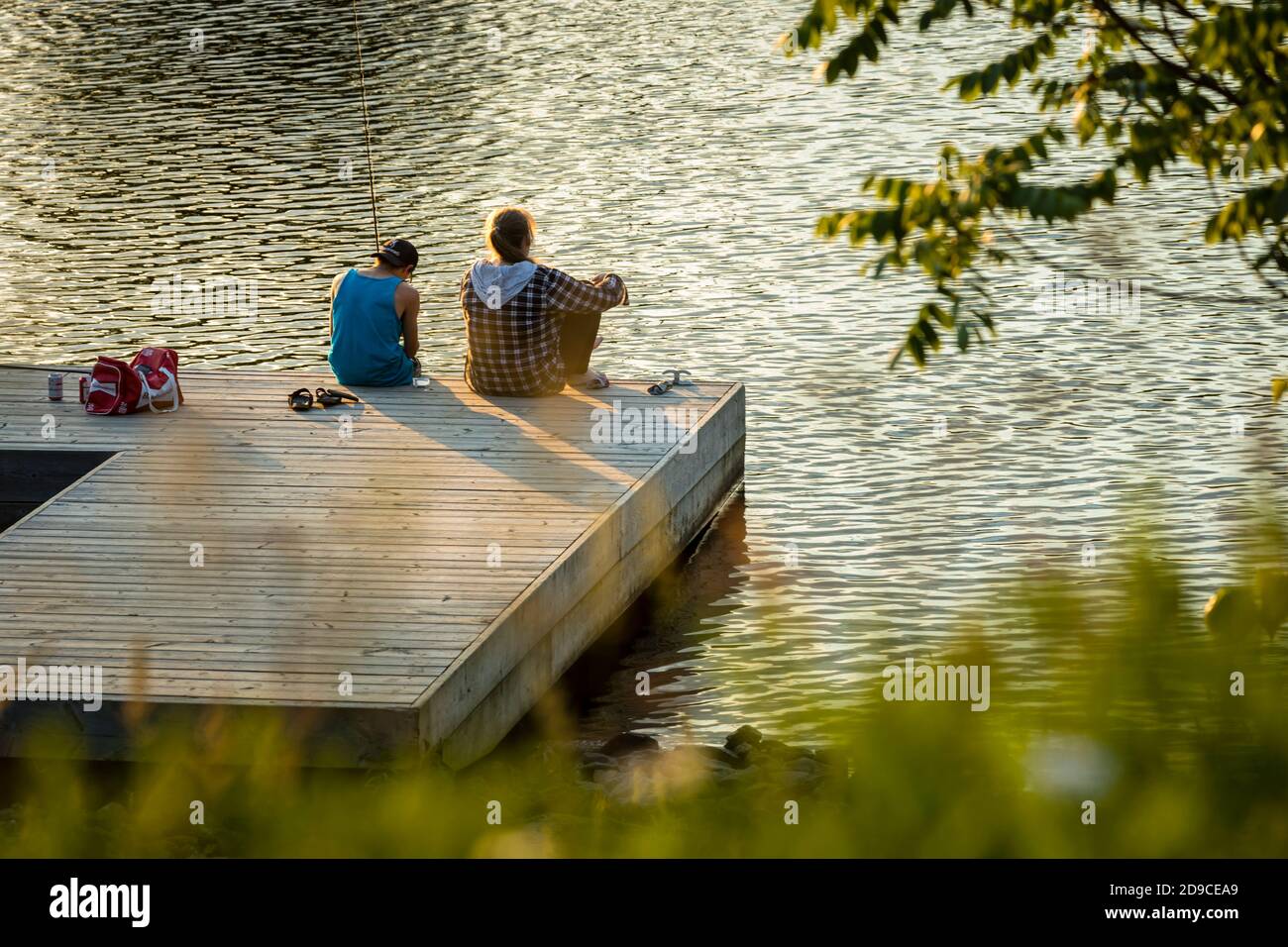 Two people firshing from a dock in Huntsville Ontario, with late afternoon light. Stock Photo