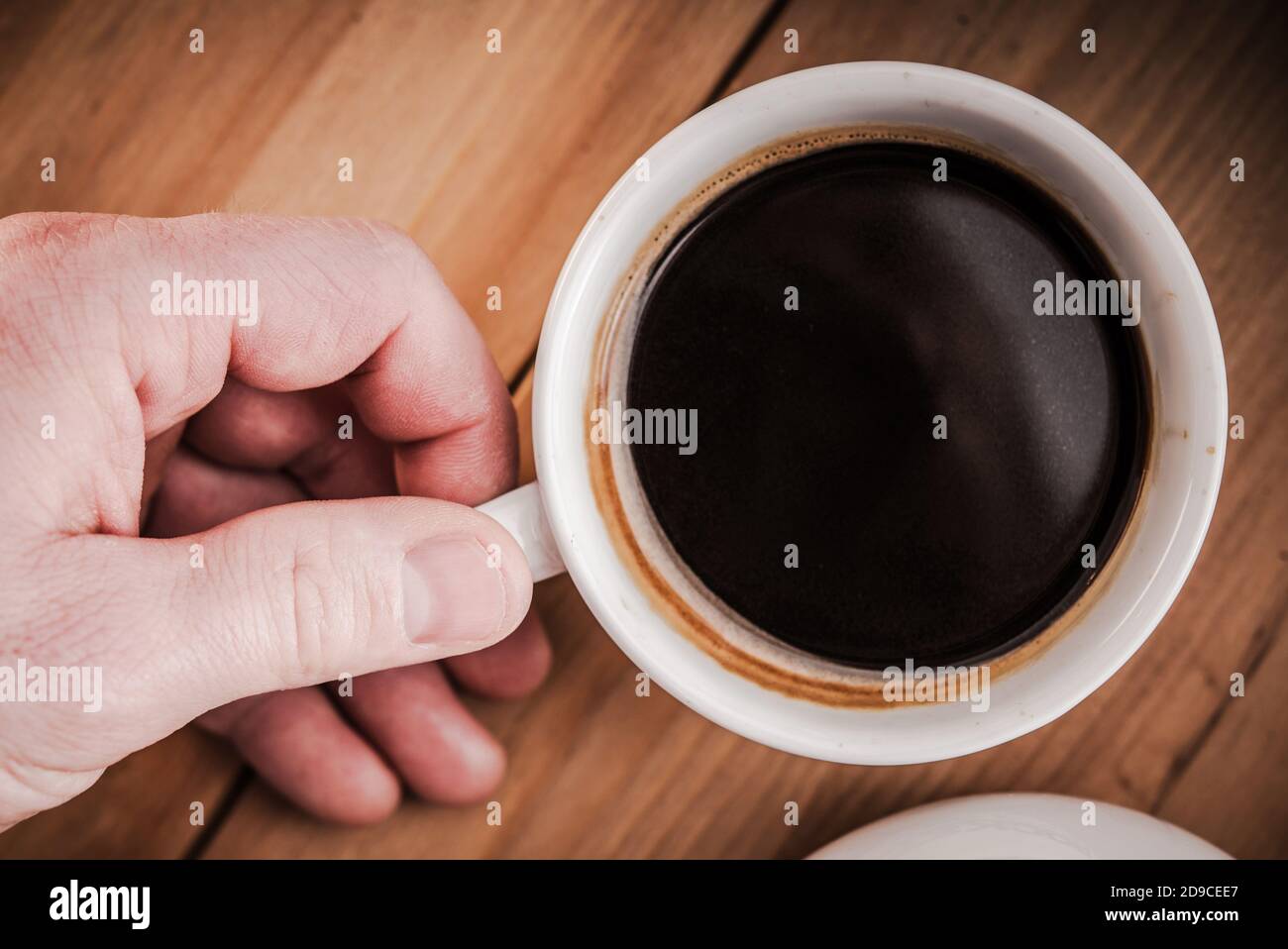 Fresh Brewed Black Arabica Coffee in White Coffee Cup. Caucasian Men Hand. Stock Photo