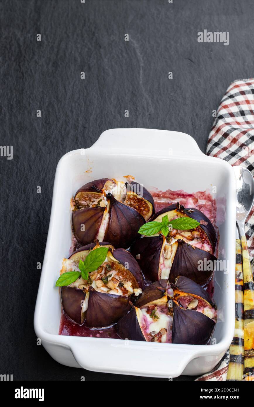 Baked fig with goat cheese and walnuts with honey on black stone