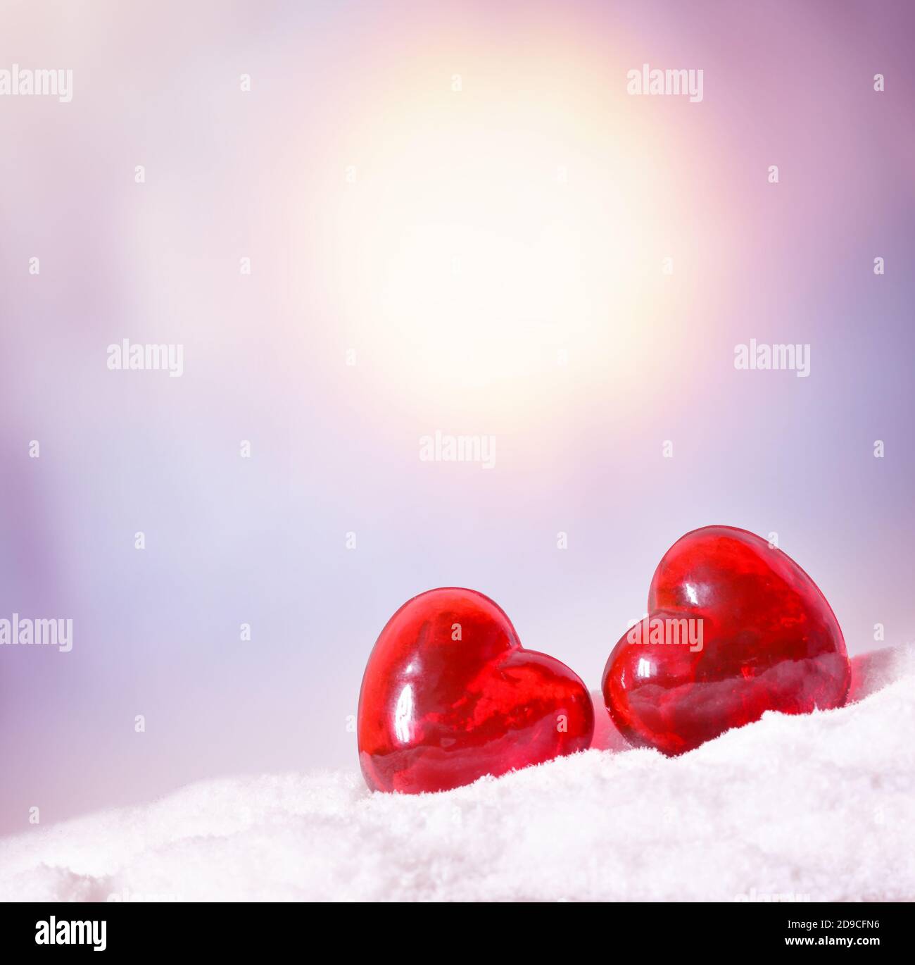 Two red glass hearts in the park on the snow. Winter festive concept. Stock Photo