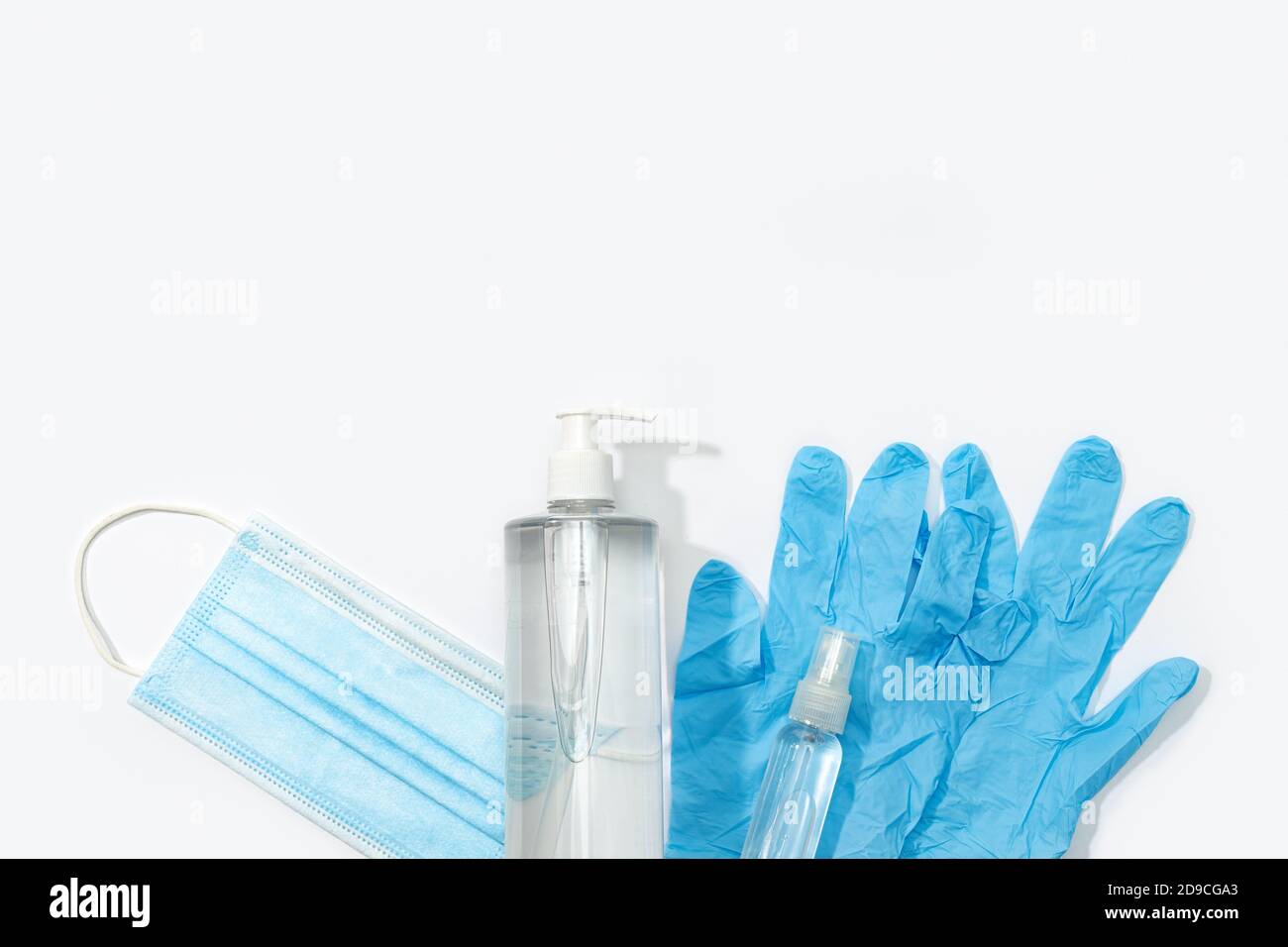Covid-19 coronavirus protection or prevention concept. Medical face mask, gloves, hand sanitizer and disinfectant spray on white background. Top view. Stock Photo