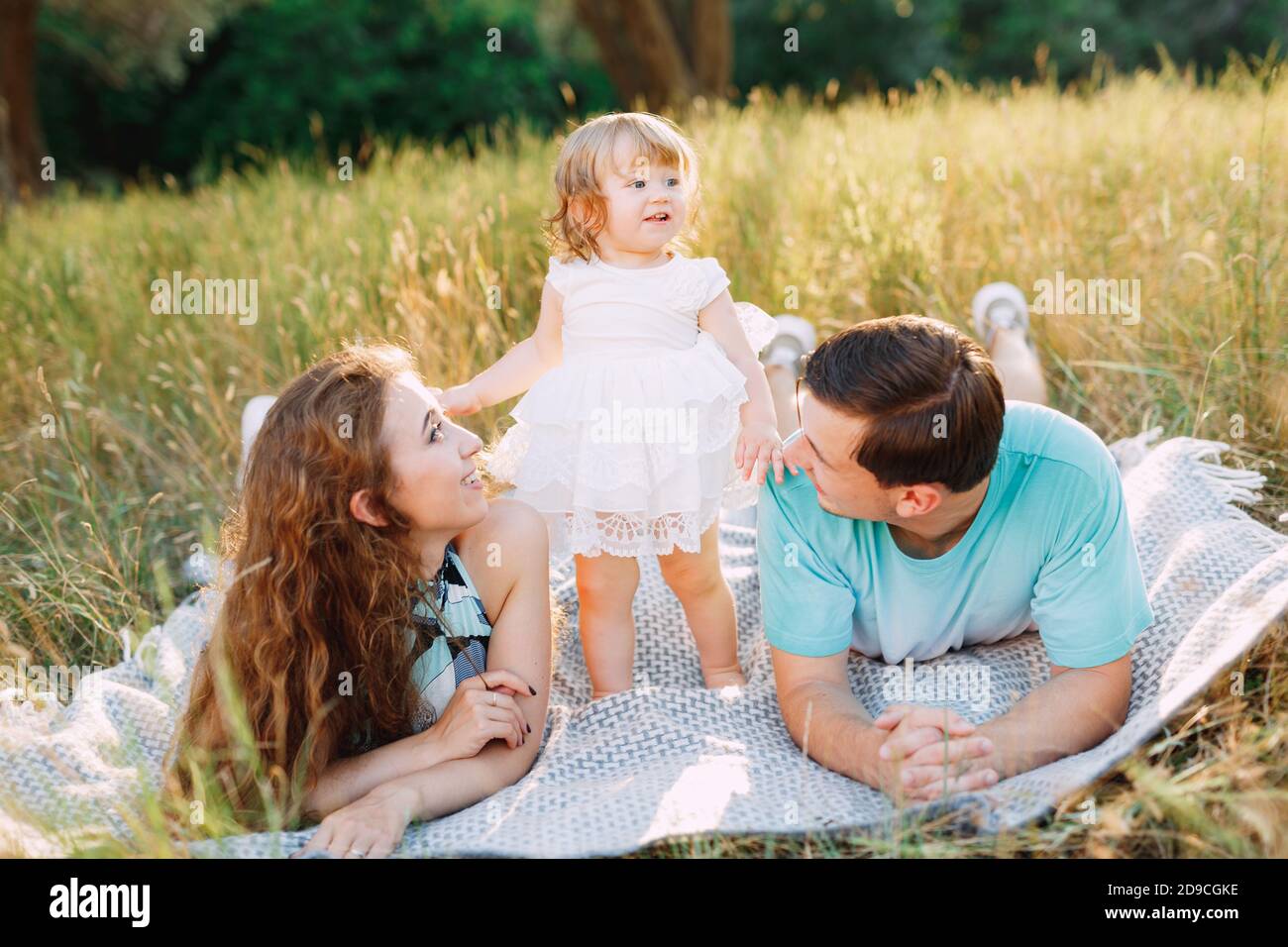 mom, dad and daughter together on a mat outdoors Stock Photo - Alamy