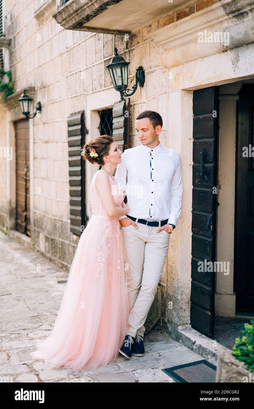 bride and groom stand hugging next to the ancient house Stock Photo - Alamy