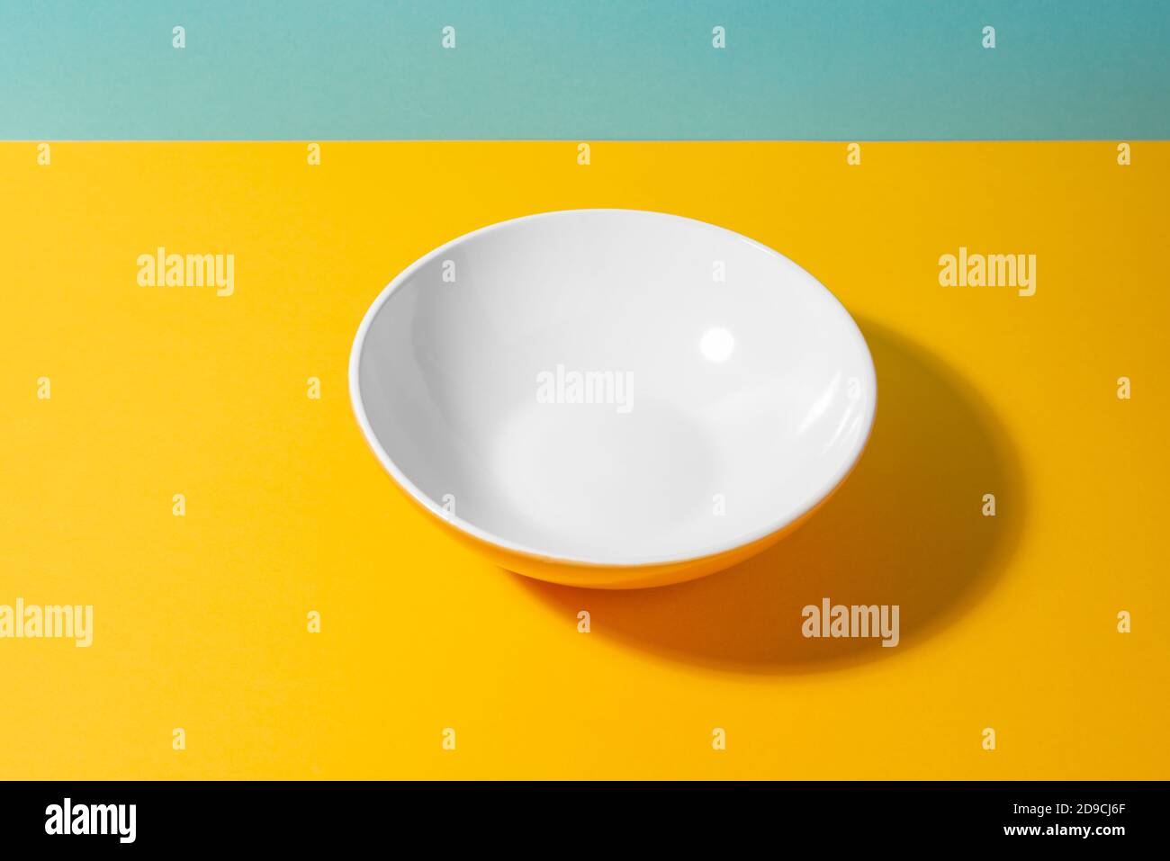 Empty deep plate on yellow and blue background Stock Photo