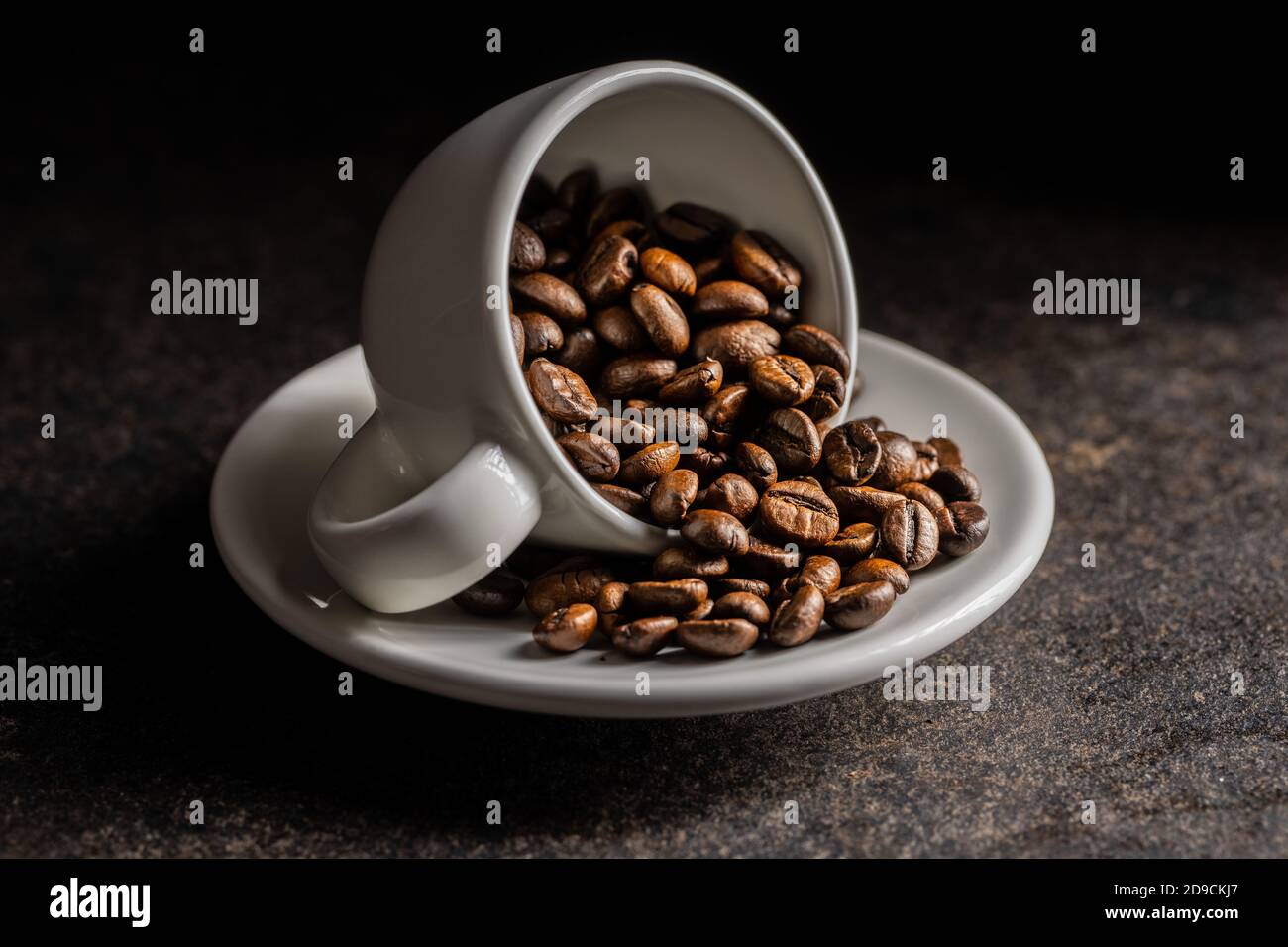 Roasted coffee beans in cup on black table. Stock Photo