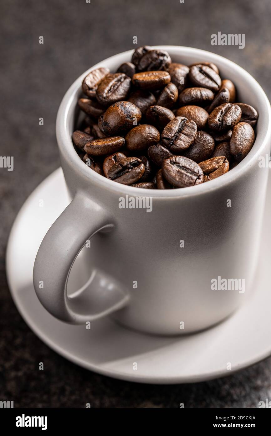 Roasted coffee beans in cup on black table. Stock Photo